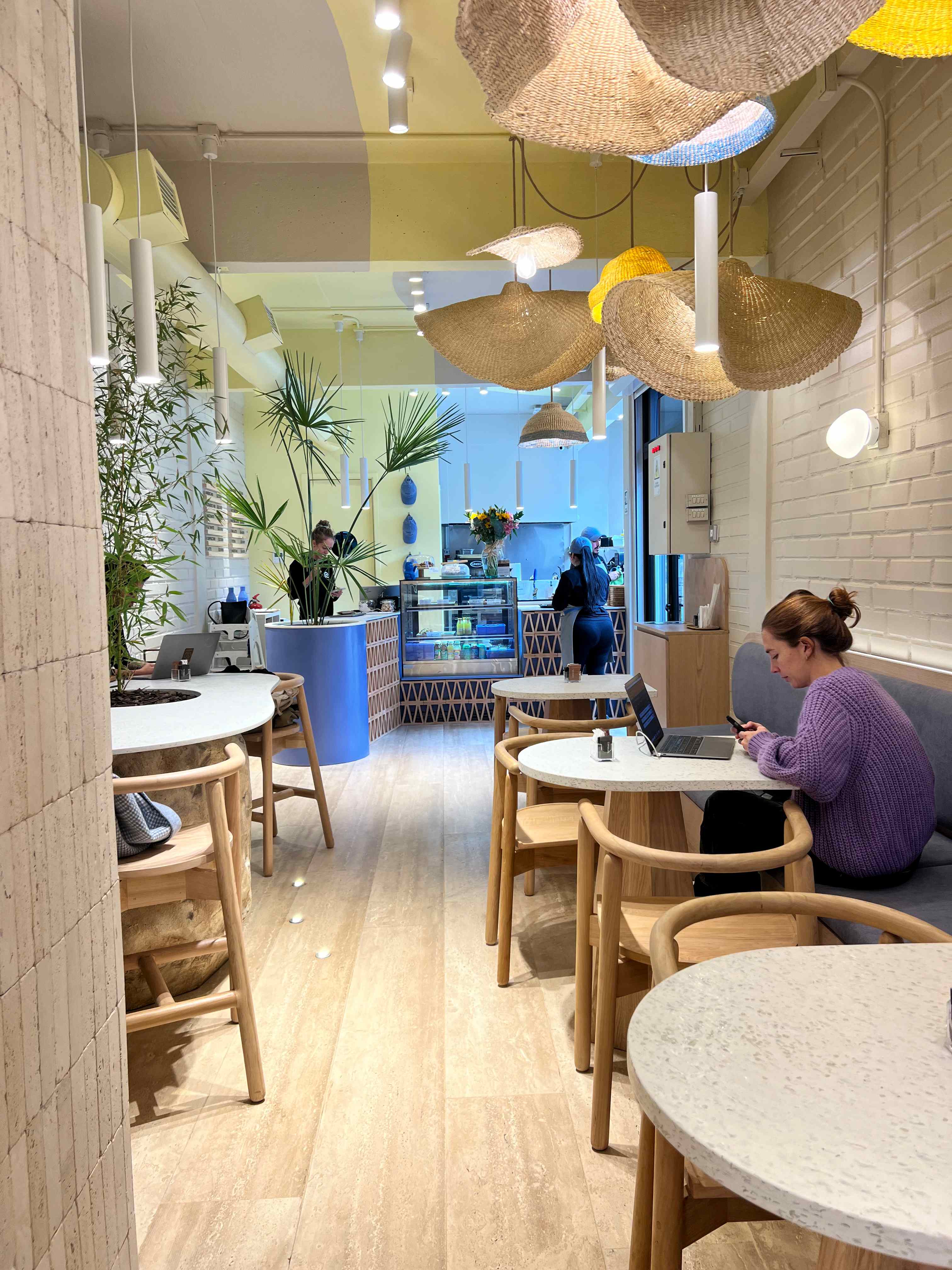 Interior de cafe con mesas de superficie Flux y mobiliario de madera