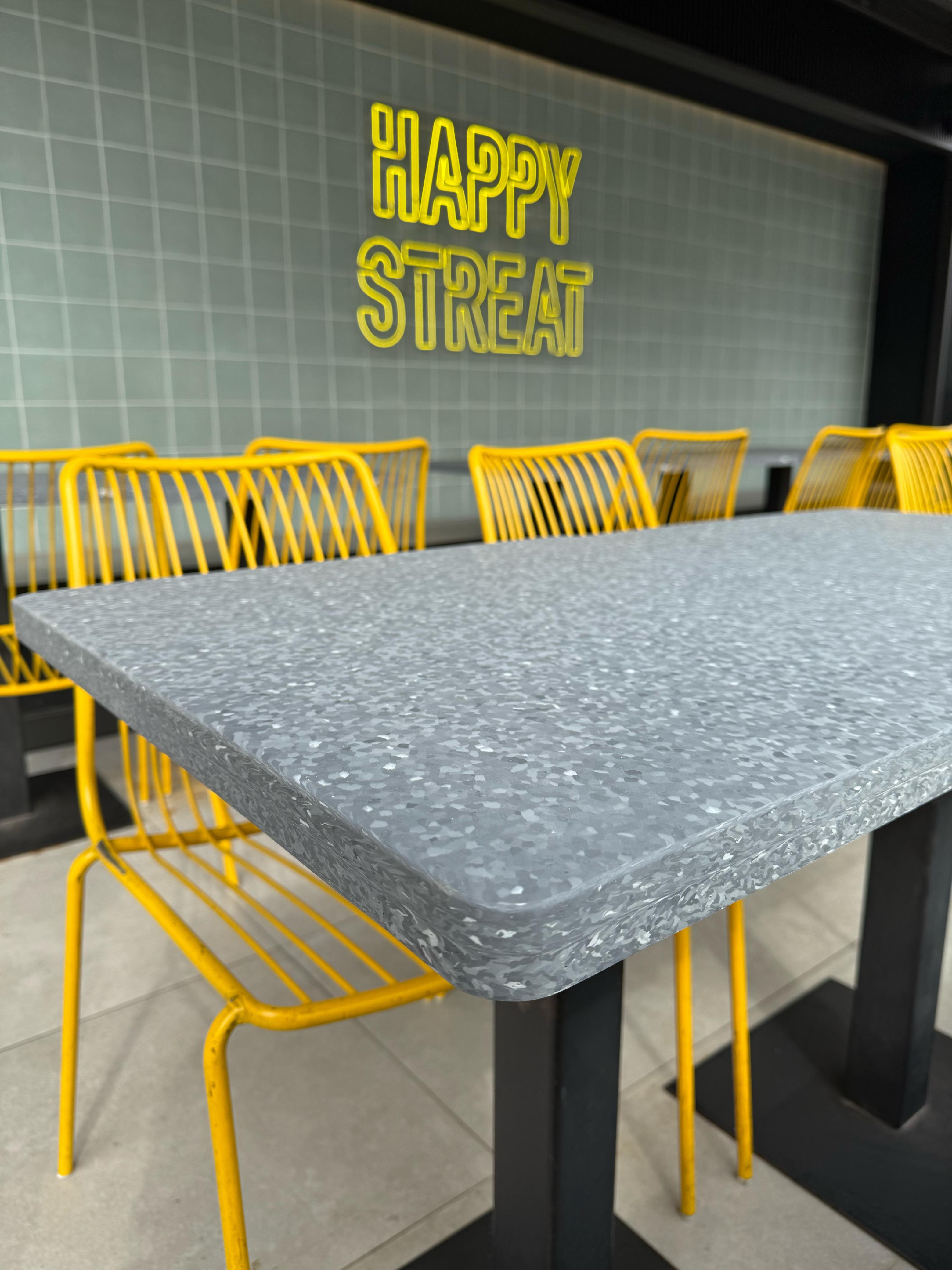 Mesa de comedor con superficie Flux tipo terrazzo y sillas amarillas