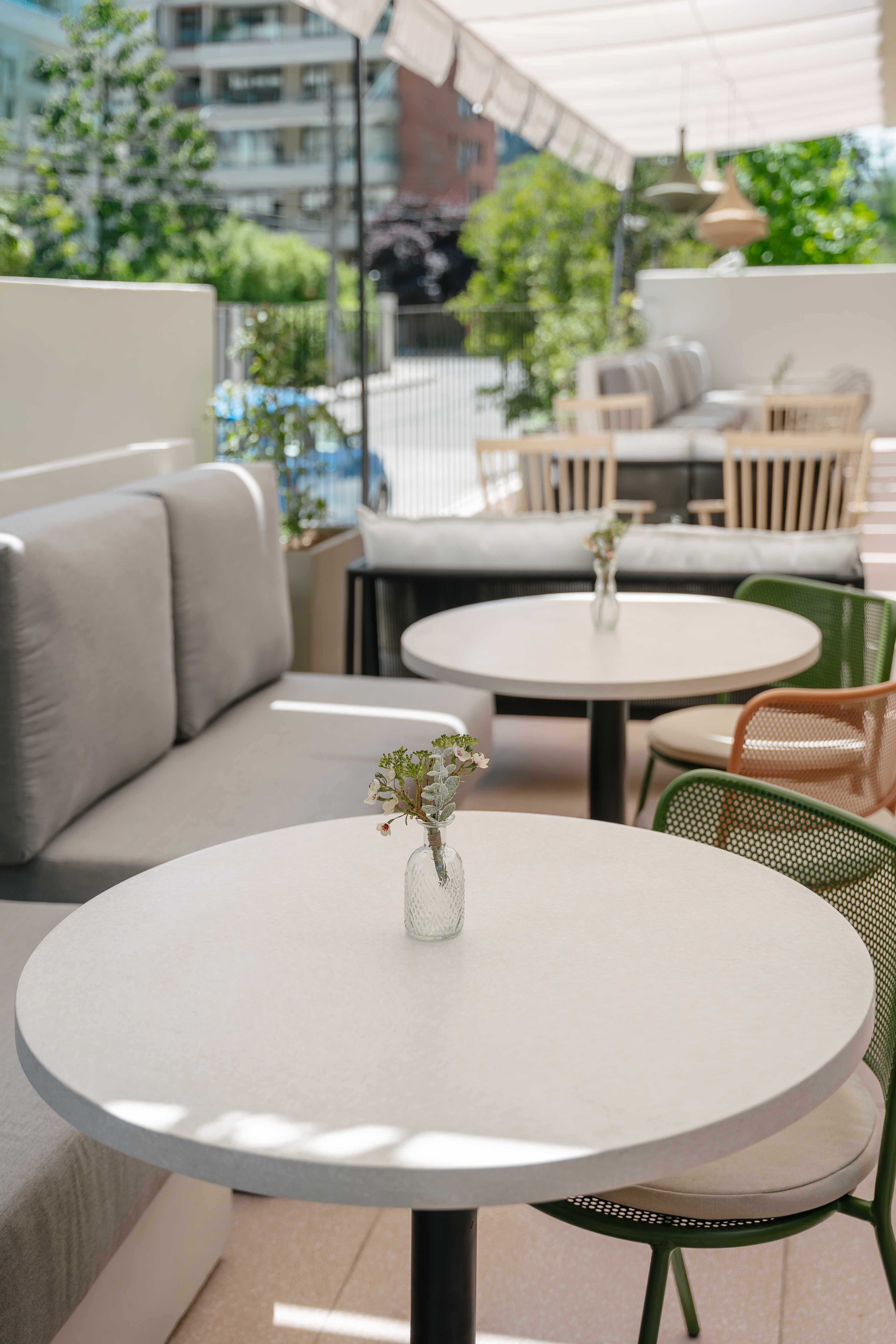 Terraza exterior con mesas de superficie Flux y sillas coloridas